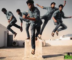 a group of men jumping in the air on top of a cement block with one man wearing flip flops