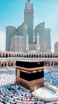 the kabab is surrounded by hundreds of people in front of large buildings with tall towers