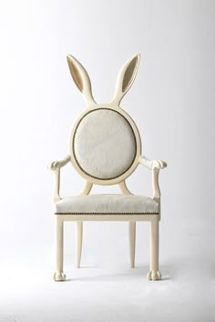 a white chair with an animal head on it's back and arms, sitting in front of a white wall