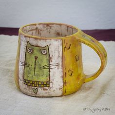 a yellow mug with a cat painted on it