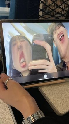 a person holding up a tablet with an image of two people on it