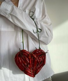 a person holding two red peppers in the shape of a heart