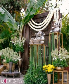 an arrangement of flowers and plants in vases next to a wooden structure with beads on it