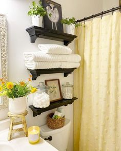 a bathroom with yellow curtains and towels on the shelf above the toilet is filled with flowers