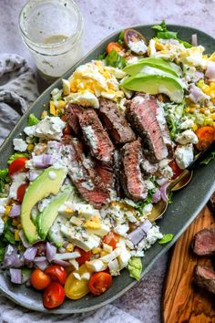 steak salad with avocado dressing on a platter next to a glass of milk