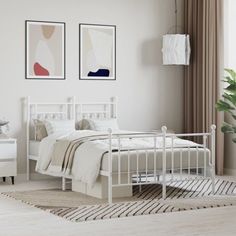 a white bed sitting in a bedroom next to two pictures on the wall above it