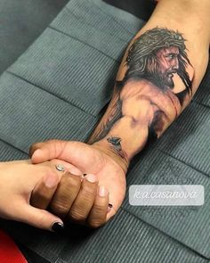 a person with a tattoo on their arm holding the hand of another person's wrist