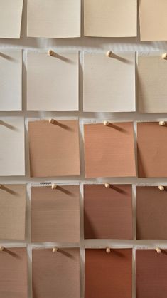 several swatches of different shades of paint on a white wall with pins in them