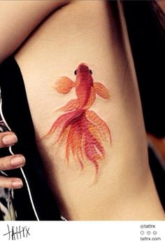 a goldfish tattoo on the side of a woman's stomach