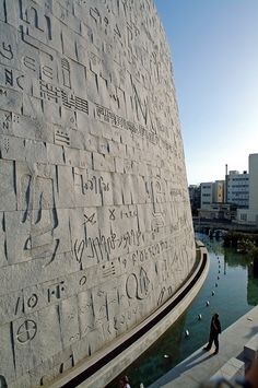 an image of the side of a building with writing on it and people walking by