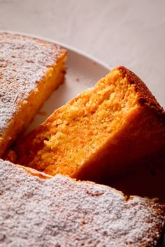 two pieces of cake on a white plate with powdered sugar and one slice missing