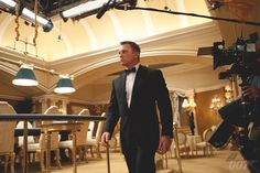 a man in a tuxedo is walking through a room with chairs and lights