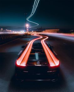 a black sports car driving down a road at night with neon lights on it's side