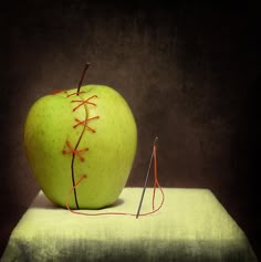 an apple with a baseball stitch on it sitting on top of a piece of cloth