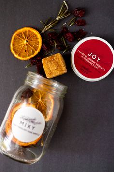 orange slices and dried herbs in a jar next to some soaps on a table