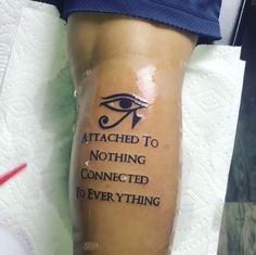 an eye tattoo on the leg of a person with words written in black and white