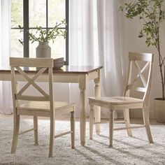 a dining room table with two chairs and a potted plant