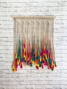 multicolored tassels hanging on a brick wall in front of a white brick wall