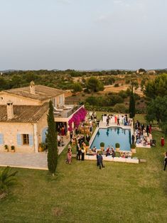 an aerial view of people standing around a pool in the middle of a lawn area