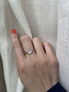 a woman's hand with an engagement ring on her finger, next to a white curtain