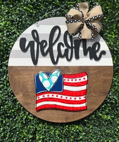 a wooden sign that says welcome with an american flag and a bow on it's head