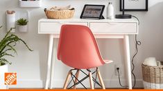 a pink chair sitting in front of a white desk with pictures on the wall above it