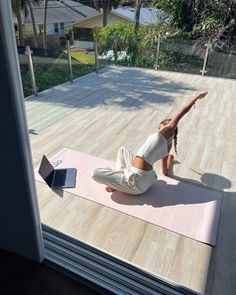 a woman is doing yoga on a mat outside with a laptop computer in front of her