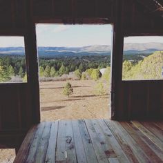 the view from inside an open cabin looking out at trees and mountains in the distance