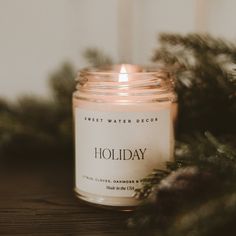 a candle sitting on top of a wooden table next to pine cones and greenery