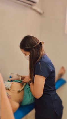 a woman in scrubs is doing something on the back of a patient's body