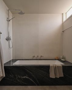 a bath tub sitting under a window next to a shower head mounted faucet