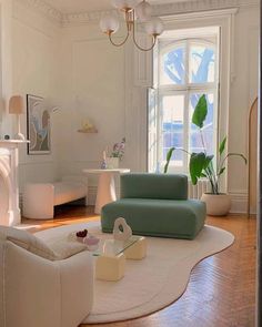 a living room filled with furniture and a fire place under a chandelier in front of a window