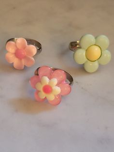 Simple flower rings! Your choice of style, all made with stainless steel adjustable bands.  Available in: Pale pink with pastel pink center (Top left of 1st photo) Pastel pink with white and hot pink center (Bottom middle of 1st photo) Mint with buttery yellow center (Top right of 1st photo) Glued down with gorilla glue and tested ensure the plastic cabochons don't come off. I would still try to avoiding pulling on the flowers with great force as this may loosen/remove the cabochon. I found that Handmade Vintage Pink Rings, Spring Pink Flower Ring Gift, Multicolor Flower-shaped Rings For Spring, Pink Ring For Spring Gift, Pink Round Jewelry For Spring, Pink Ring As Spring Season Gift, Spring Gift Pink Ring, Spring Gift Pink Rings, Pink Rings Suitable For Spring Gift