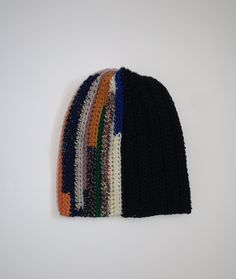 a multicolored knitted beanie sits on a white surface