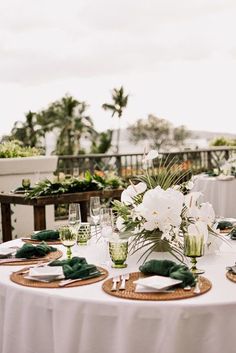 the table is set with white flowers and place settings