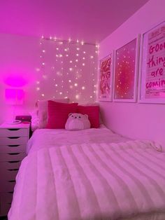 a bedroom with pink lights and pictures on the wall above the bed, along with a teddy bear