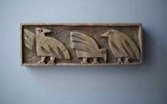 three birds carved into a wooden plaque on a wall