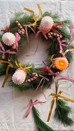 a wreath made out of pine branches and ribbons with candy in the shape of flowers