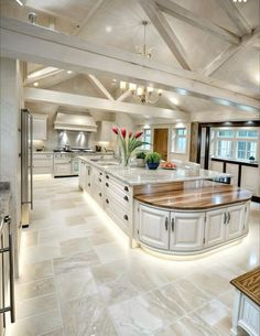 a large kitchen with white cabinets and marble counter tops is lit by recessed lights