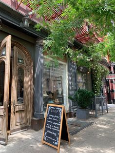 a sign is in front of a building with an open door on the sidewalk next to it