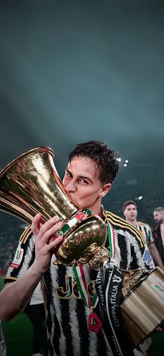 a man holding a trophy in his right hand and wearing a striped shirt on the other side