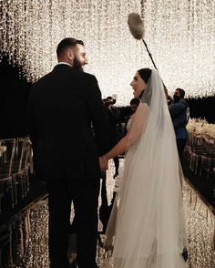 a bride and groom standing in front of a chandelier filled with white lights