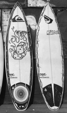 three surfboards sitting next to each other in front of a wooden wall with writing on them