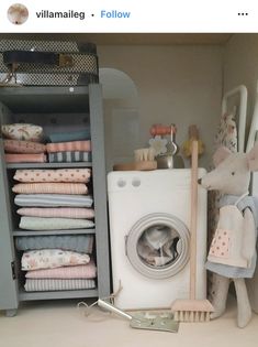 a toy mouse sitting next to a washer in a room filled with folded towels