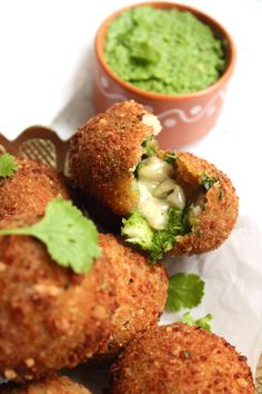 some broccoli and cheese balls are on a plate next to a small bowl