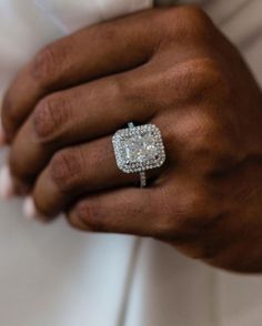 a close up of a person's hand wearing a diamond ring