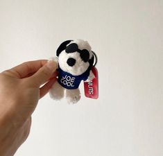 a hand holding a small stuffed animal with a tag on it's collar and ear