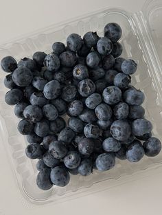 a plastic container filled with blueberries on top of a table