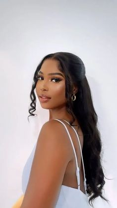 an image of a woman with long hair wearing a white top and gold hoop earrings