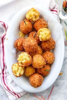 a white bowl filled with tater tots on top of a table next to other food